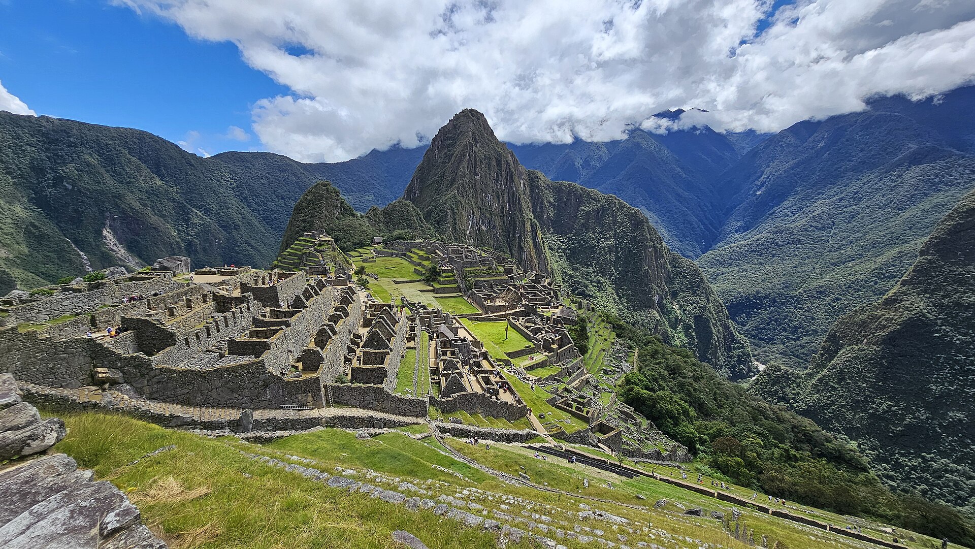 Machu Picchu's stone temples and terraces beneath Huayna Picchu, surrounded by the green Urubamba valley